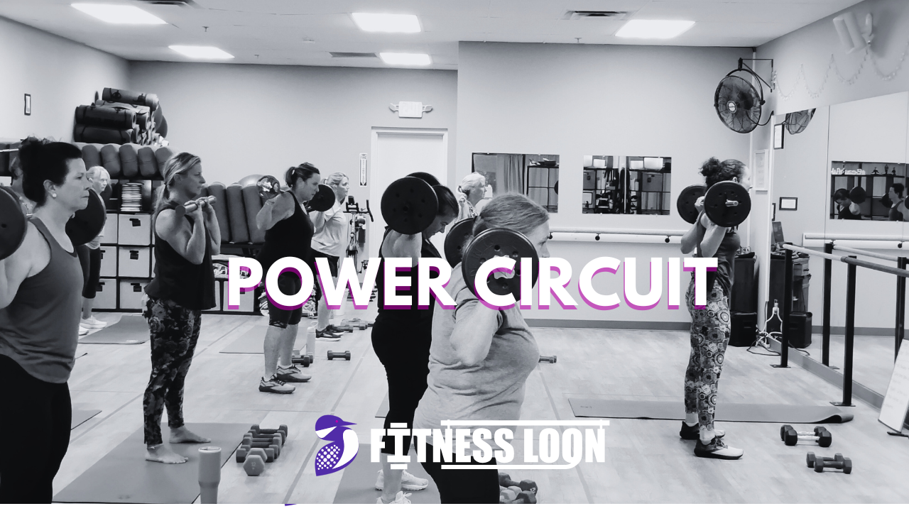Group fitness class performing barbell power circuit workout