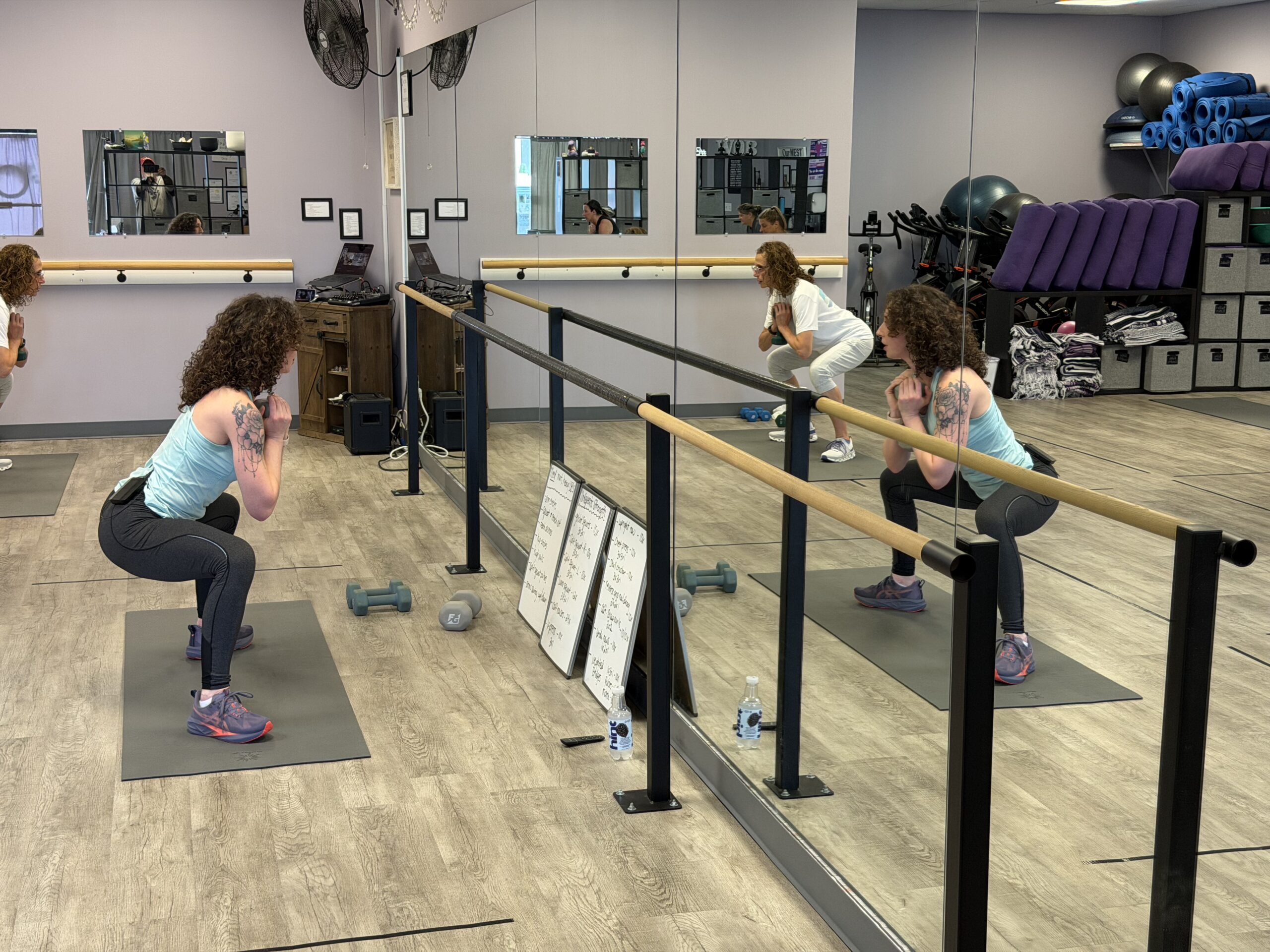 Women doing squats in mirrored fitness studio