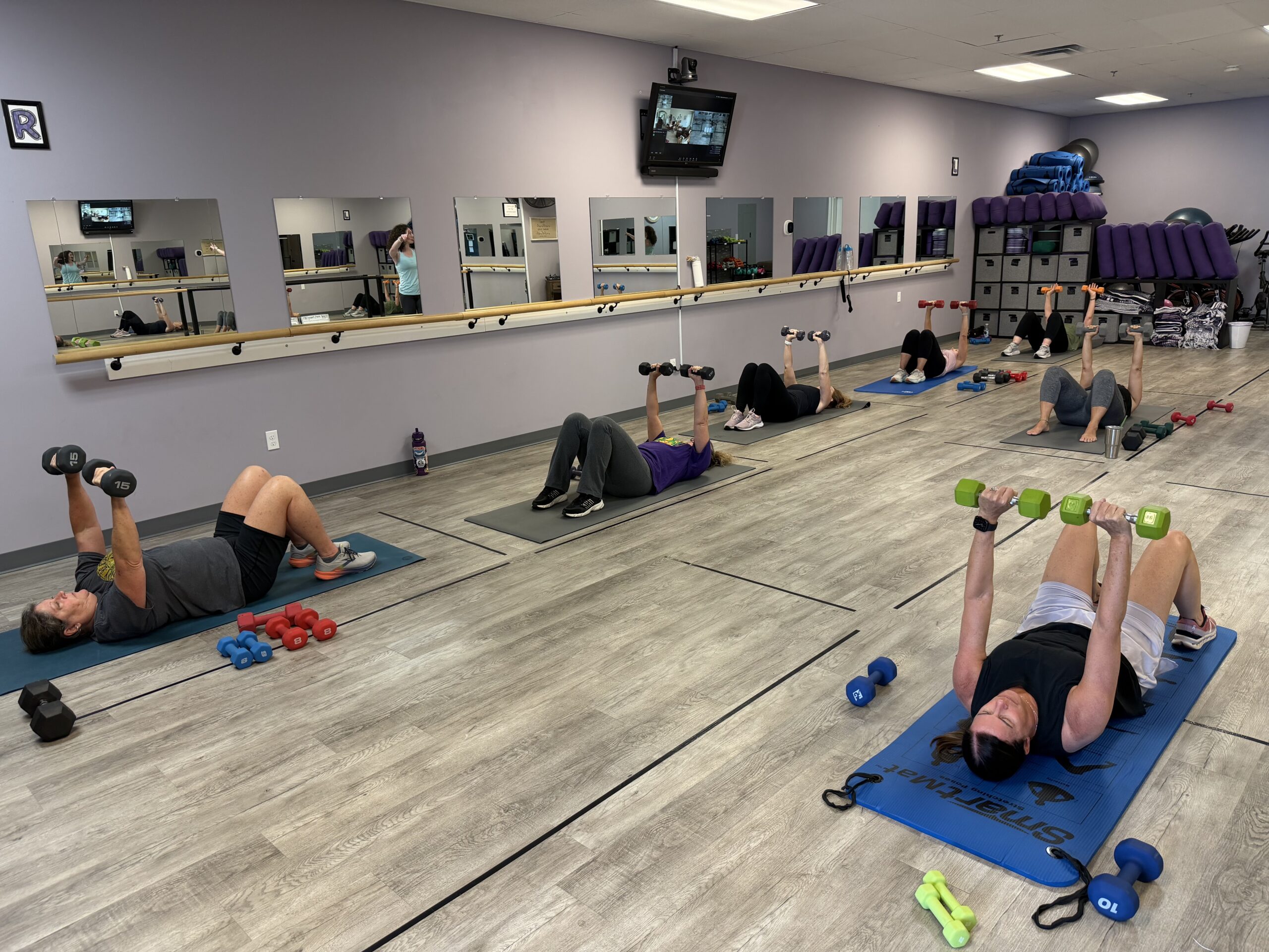 Group fitness class doing dumbbell chest presses indoors